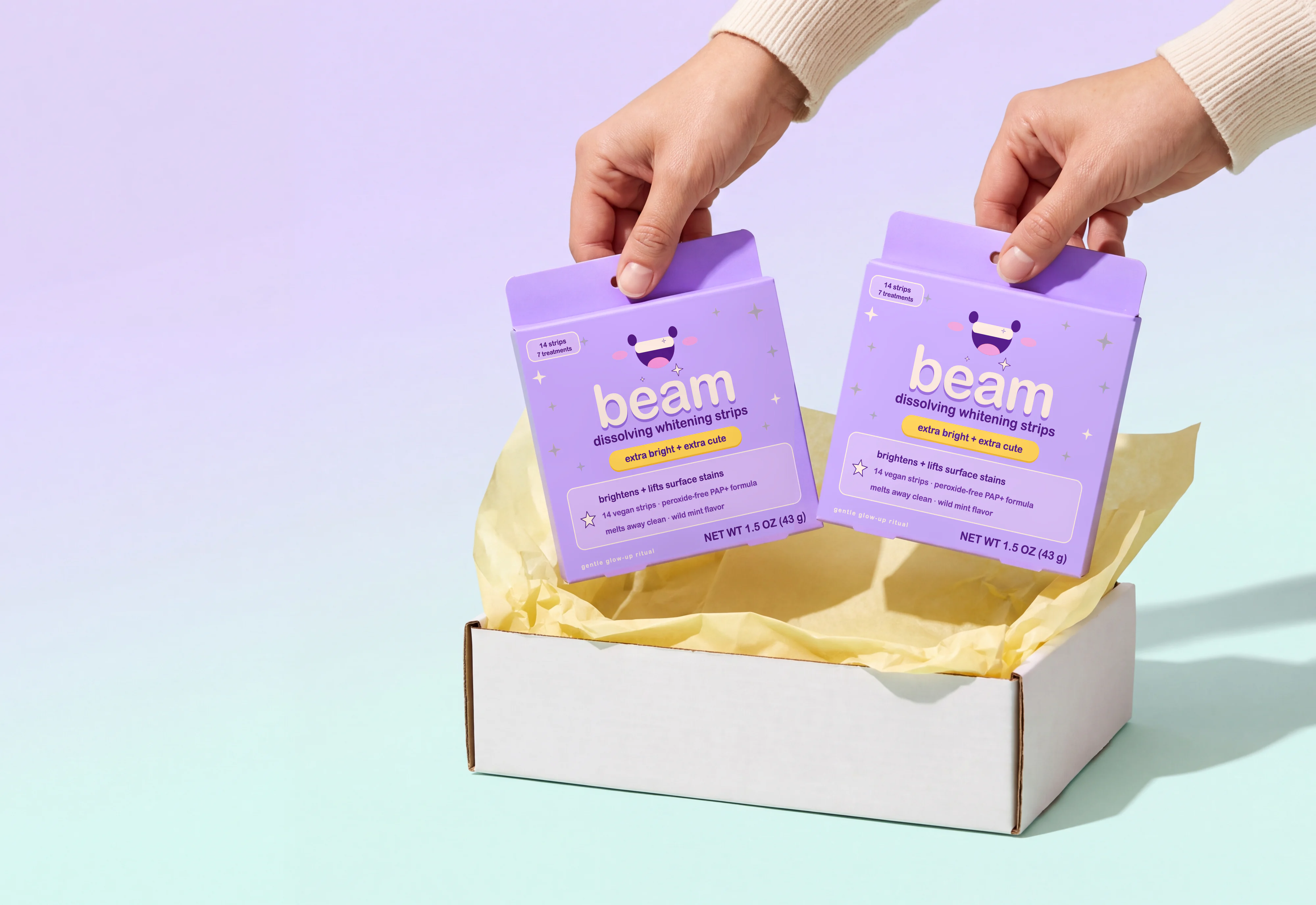 Two hands lifting boxes of beam dissolving whitening strips out of a delivery box.